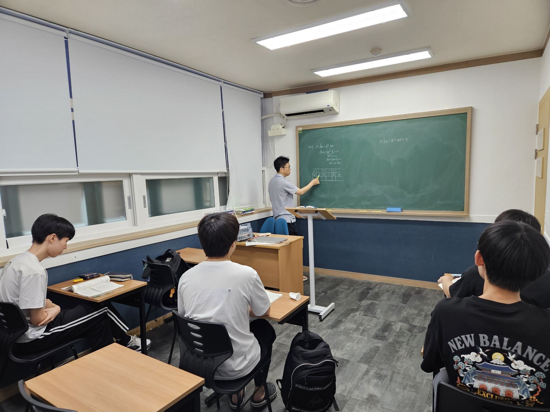 원장이 칠판에 함수의 증감표를 판서하며 수업하는 모습